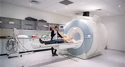 A doctor stands next to a patient getting ready to go into an MRI machine
