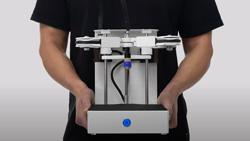 A close up of a person holding a 3d printer to highlight its small size.