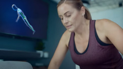 A person is doing a pushup and there is a monitor in the background displaying a wire-frame figure doing a pushup