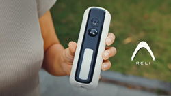 A closeup of a person holding the pill-shaped, black and white, Reli Light Cam D1 security camera