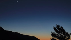 A view of the horizon at sunset. One star can be seen in the sky.