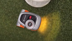 An orange and gray robot lawn mower is seen from above.