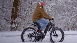 A person is riding a carbon black ebike through the snow.