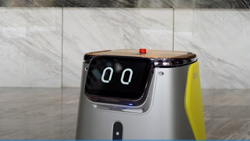 A waist-high, silver and yellow cleaning robot, with eyes on an LCD screen