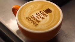 An image printed on light colored coffee in an orange cup. The text reads: Keep calm and drink coffee.