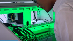A technician peers into a submersed computing system that has a green glow