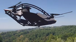 A black and white, personal EVTOL is flying through the air over tree covered hills