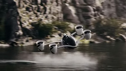 A black and white hovercraft is flying above the water creating a wake.