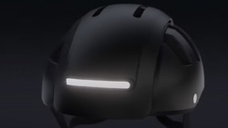 A darkened image of a commuter helmet with a thin, bright white light bar going across the back