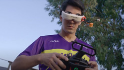 a young man facing the camera looking down wearing FPV goggles and holding a drone controller