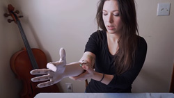 A person behind a table is adjusting a prosthetic arm at the elbow.