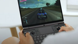 A POV closeup of a person playing a racing game on a gray book-sized gaming PC.