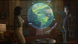Two people are standing with mixed reality headsets on looking at a holographic image of the earth in between them