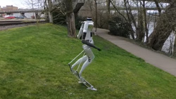 a humanoid robot with no head climbs down a fairly steep wet hill