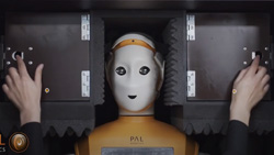 a closeup of a humanoid robot's head and shoulders inside of a metal shipping box