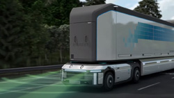 A long, white and grey semi-truck with no windows is shown on the highway. Light green beams of light are shown emitting from the front of the truck depicting LIDAR beams.