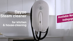A white oval shaped device with black hoses attached is floating in mid-air. A white kitchen is seen in the background. Text reads Dayoo steam cleaner.