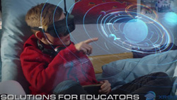 A child is wearing VR goggles while lying in bed and pointing at a hologram of the solar system