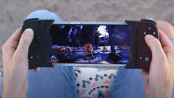 A POV view of a person holding a gaming console with a game playing on the screen.