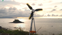 A small wind turbine sits at the edge of the ocean