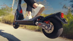 A view from ground level shows a person performing a short jump on an electric scooter.