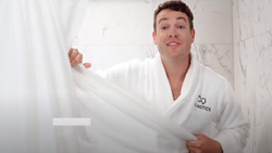 A person in a white robe is standing in the shower
