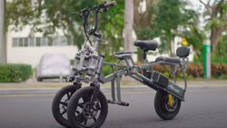 A gray three-wheeled electric bike shown outdoors.