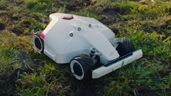 A white and black robot lawn mower looks like the front half of an Indy race car.