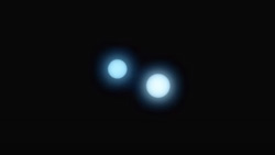 A closeup of two glowing objects in an otherwise all black night sky