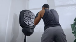 A view from behind a person with boxing gloves on in a boxing posture facing a stand mounted punching surface.