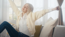 A person is sitting on a couch stretching.