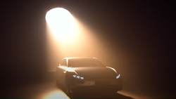 A car is shown in a darkened room with a strong spotlight to the rear of it shining down.