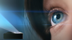 A closeup of a person's eye from the side. A black box with beams of light coming from it is in the lower left with a darkened background. The beams of light point away from the person.