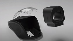 An exploded view of a dark gray desktop mouse that has its top clear cover open with a bulky ring shaped device floating above it that normally fits inside the desktop mouse