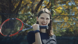 A person is playing tennis while wearing a black wrist band device